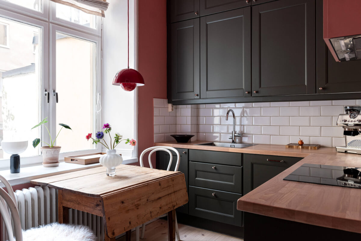 An Elegant Stockholm Apartment with a Pink and Black Kitchen 12 small kitchen black cabinets pink walls wooden table