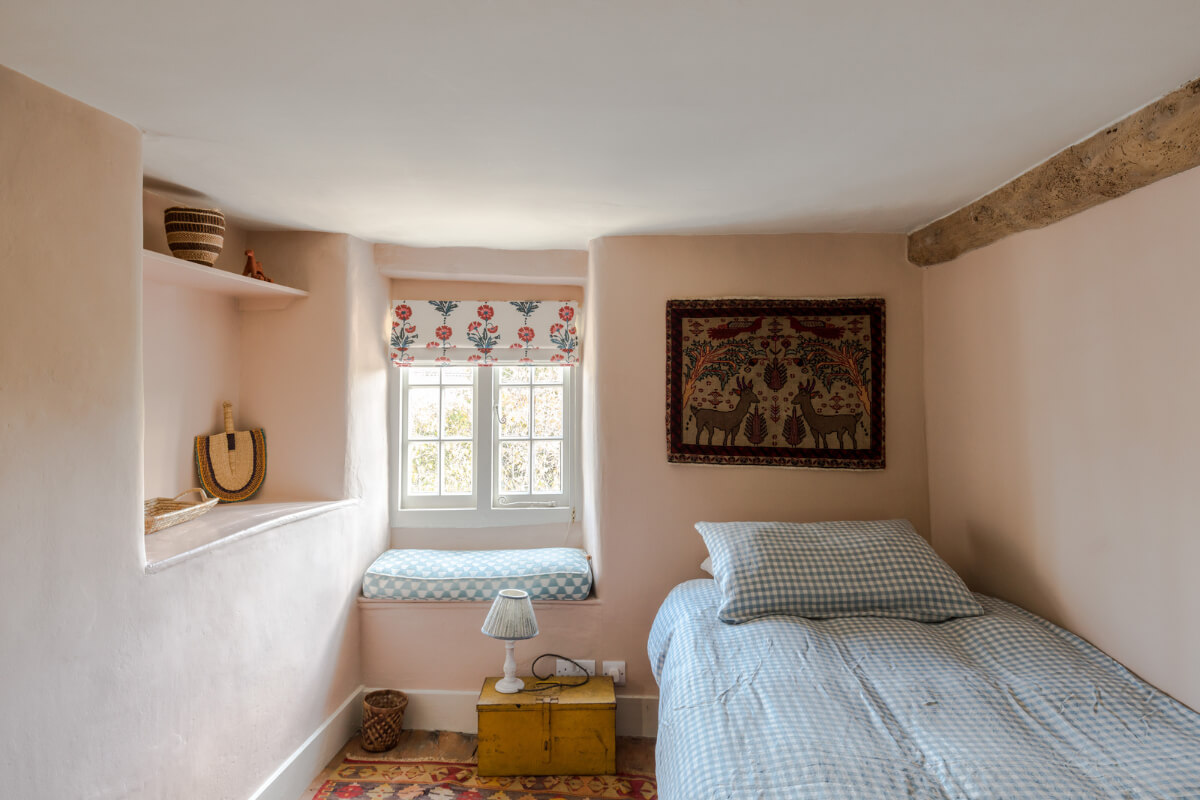 A Carefully Selected Color Palette in an 18th-Century English Cottage 11 small pink bedroom with exposed beam and window seat