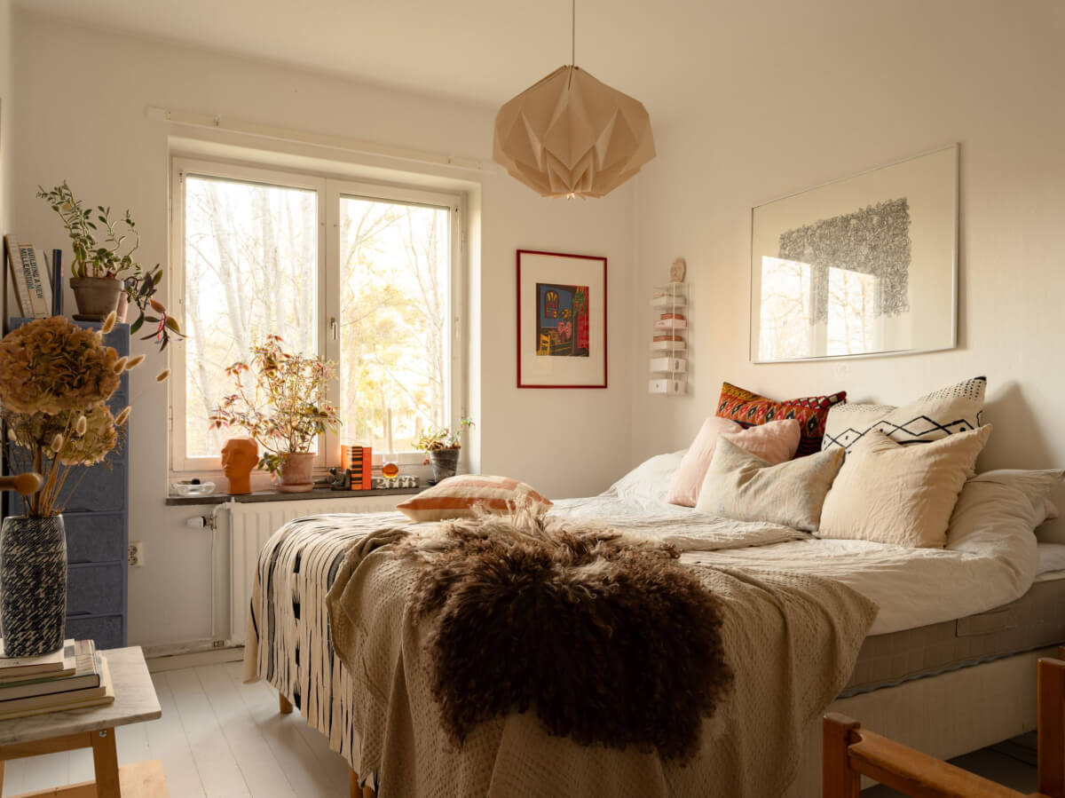 A Charming Midcentury Apartment with a Reading Room 23 white bedroom with layered textiles and blue cabinet