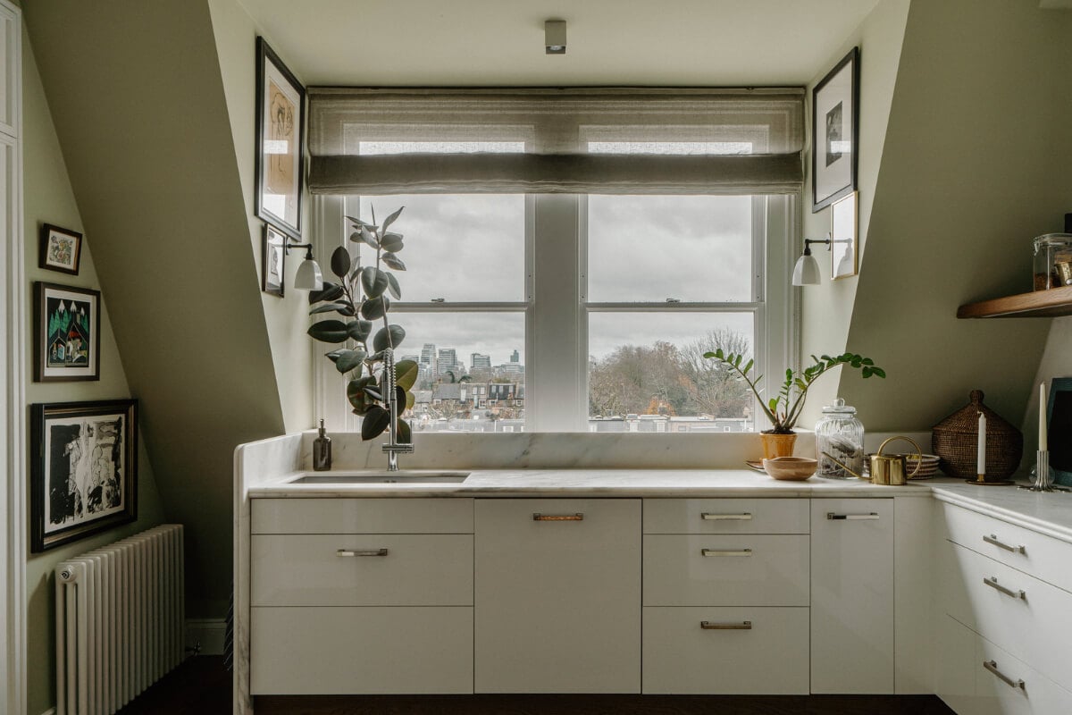 A Cozy Art-Filled Attic Apartment in London 9 white kitchen with marble countertop and olive green walls