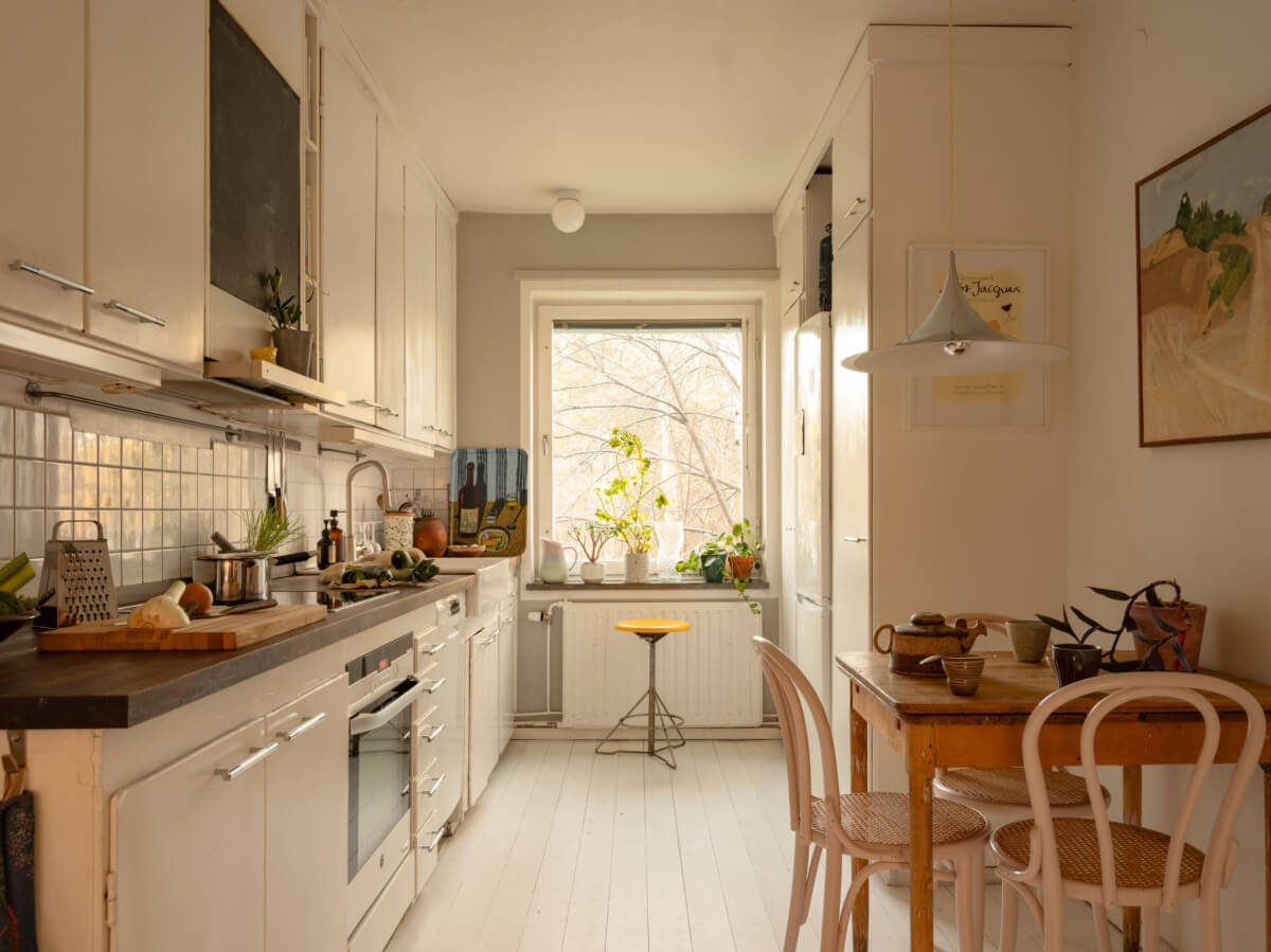 A Charming Midcentury Apartment with a Reading Room 10 white kitchen with small wooden table