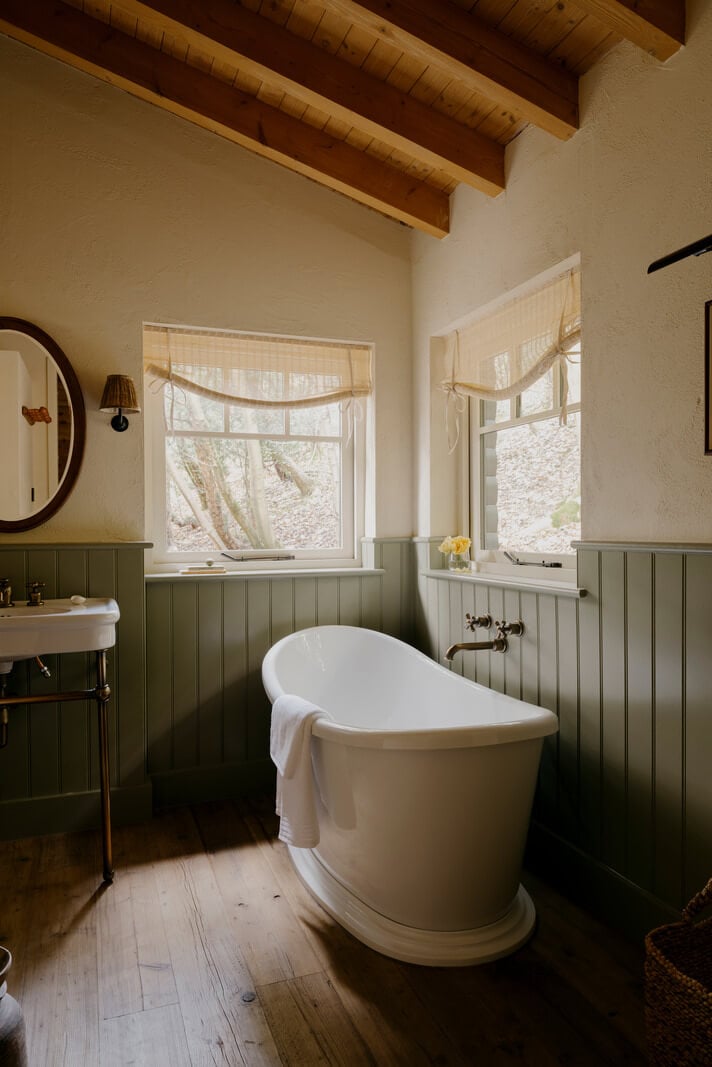 A Cozy and Contemporary Take on a Traditional Log House 16 bathroom pitched wooden ceiling freestanding bath tongue and groove paneling