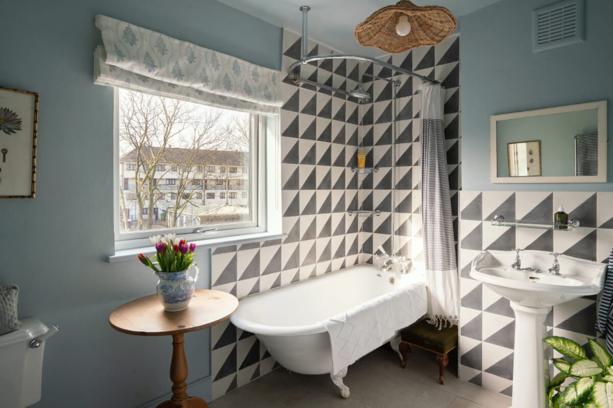 A Bright Victorian House with Plaster Walls and Blue Rooms 23 blue bathroom with freestanding bath and black and white geometric tiles
