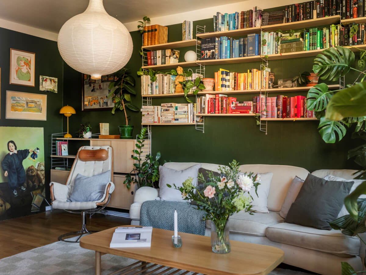 Cozy Plant-Filled Interiors in a 1940s Apartment 3 deep green walls living room bookshelves