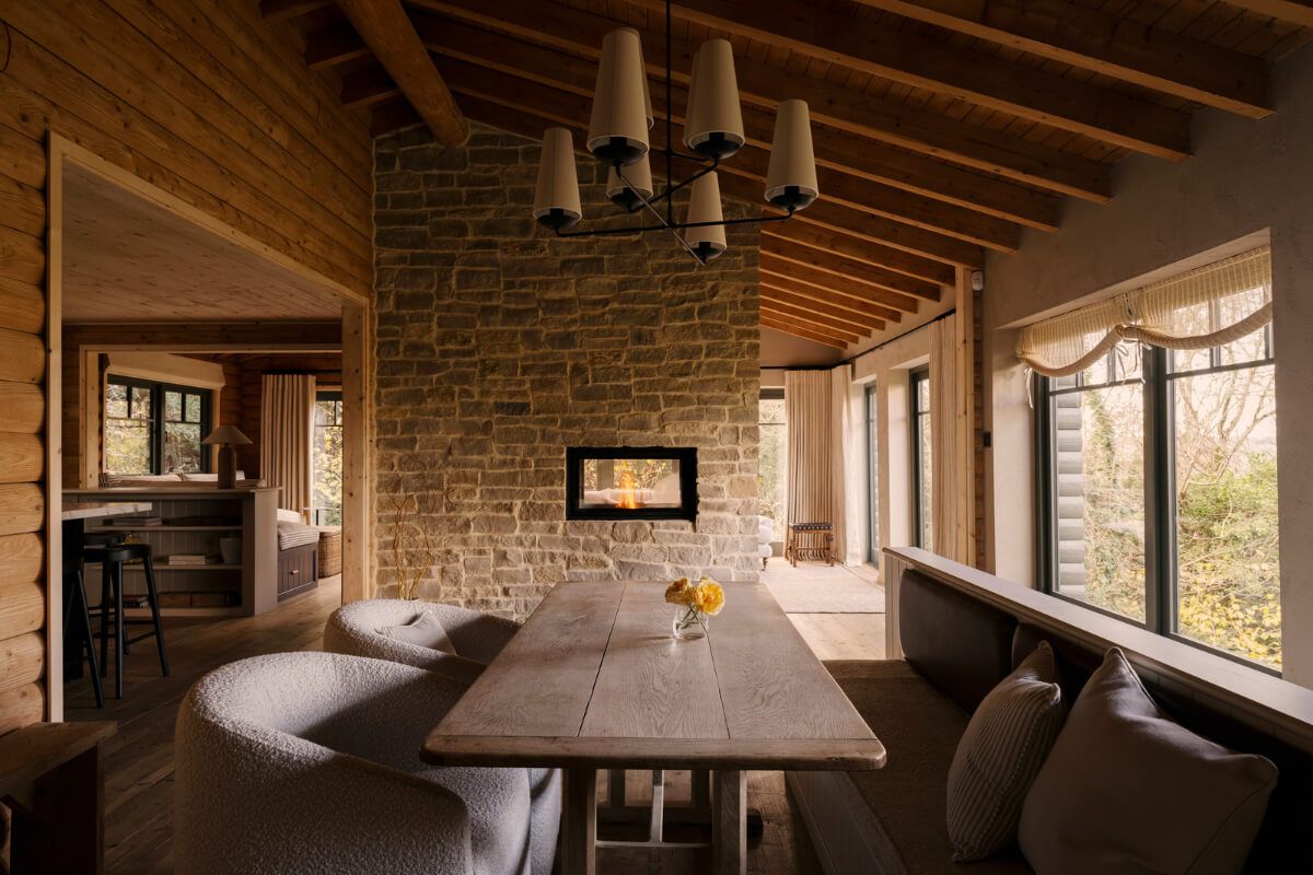 A Cozy and Contemporary Take on a Traditional Log House 11 dining room stone wall pitched wooden ceiling