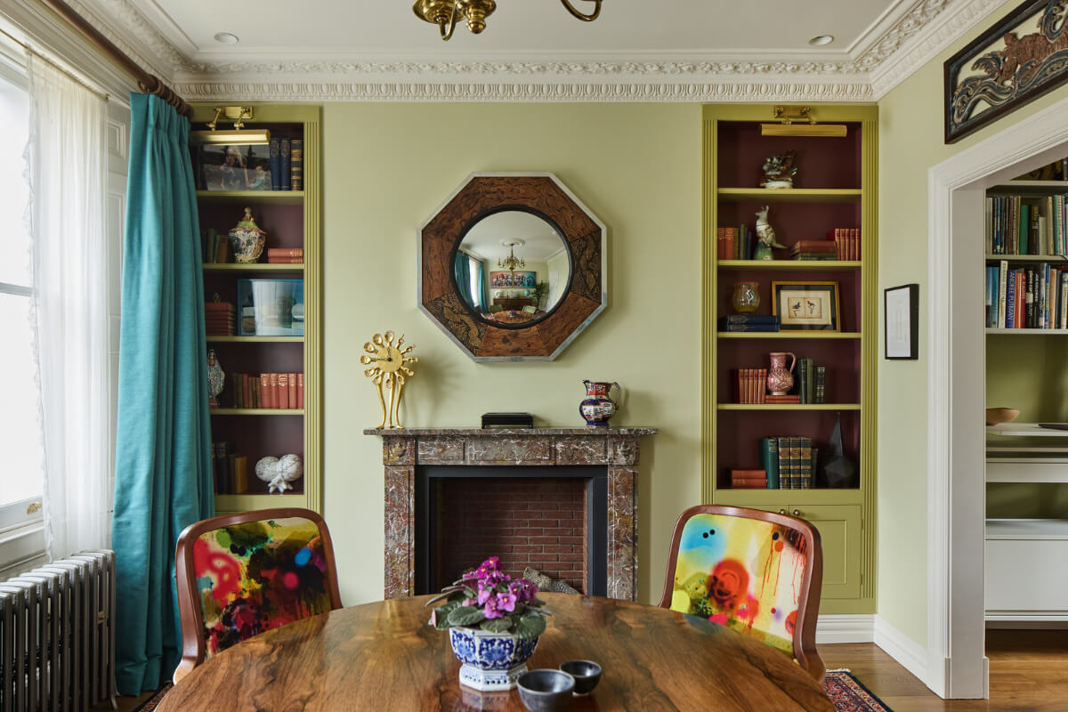 A Renovated Early Victorian Townhouse Decorated in Green Tones 7 green dining room round table fireplace flanked by bookcases