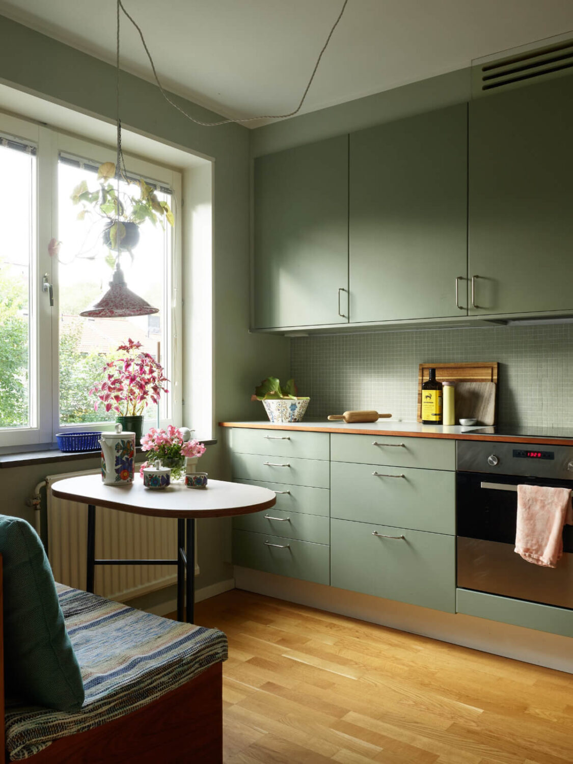 A Lovely Color Palette in a Midcentury Apartment in Sweden 13 green kitchen with breakfast table