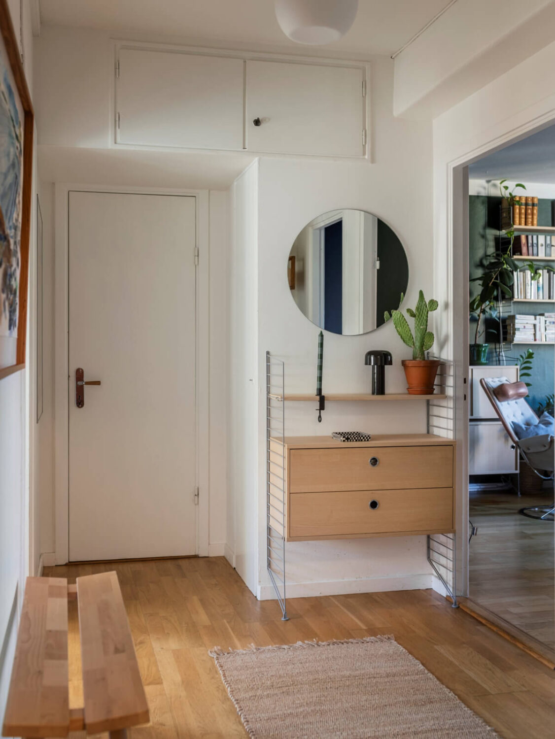 Cozy Plant-Filled Interiors in a 1940s Apartment 21 hallway string shelves cabinet round mirror