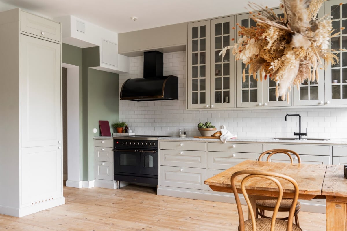 A Light Swedish Apartment with a Green Living Room 7 light green kitchen with white backsplash tiles