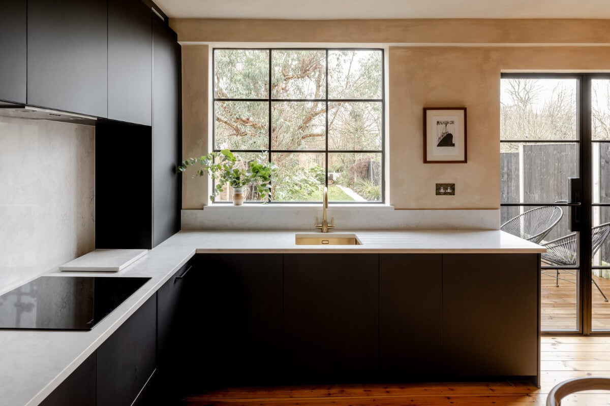 A Contrasting Color Palette in a Renovated Terrace House 5 modern kitchen black cabinets window overlooking garden