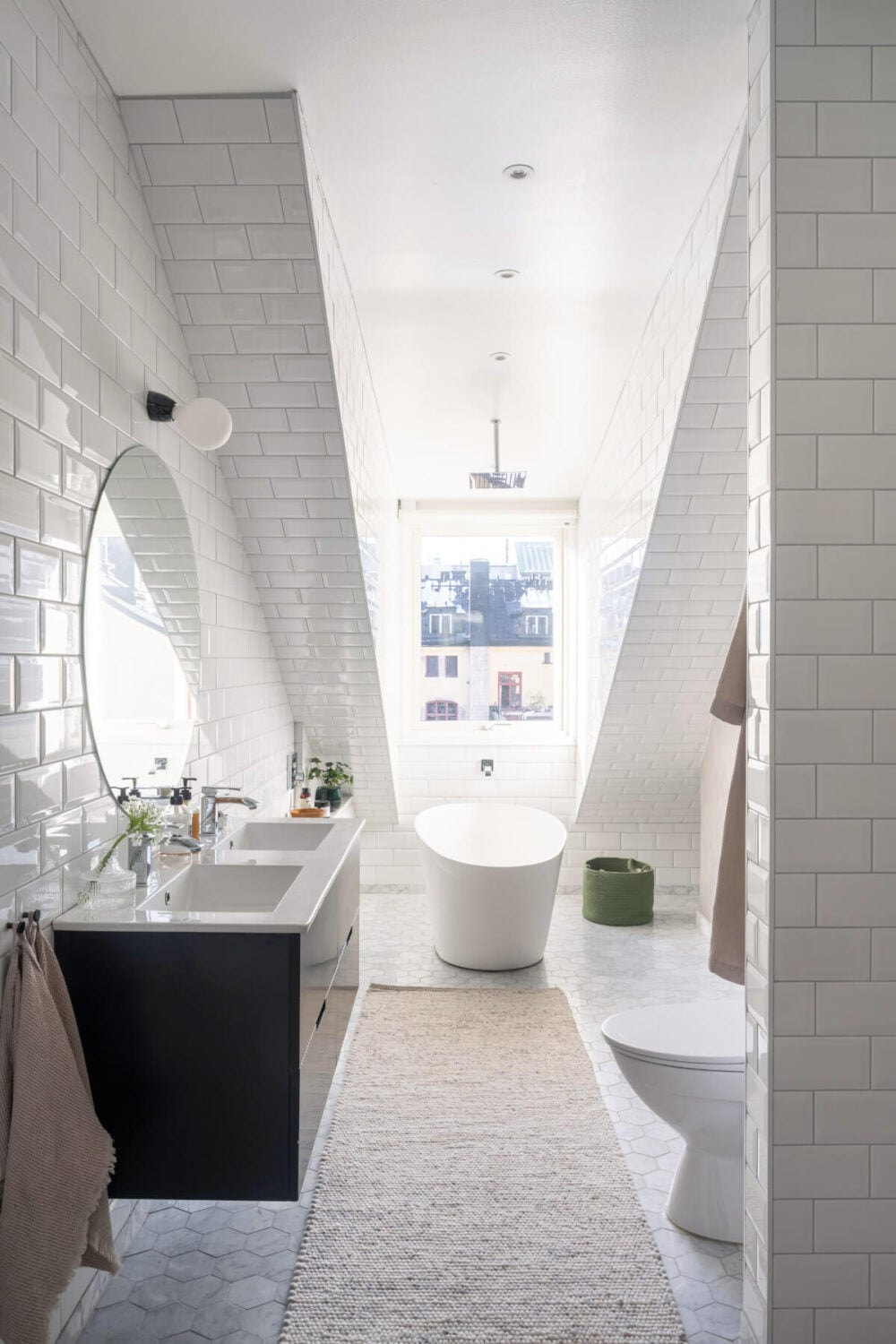 A Light Penthouse Apartment with Built-In Bookshelves 18 white bathroom slanted ceiling marble floor tiles freestanding bath