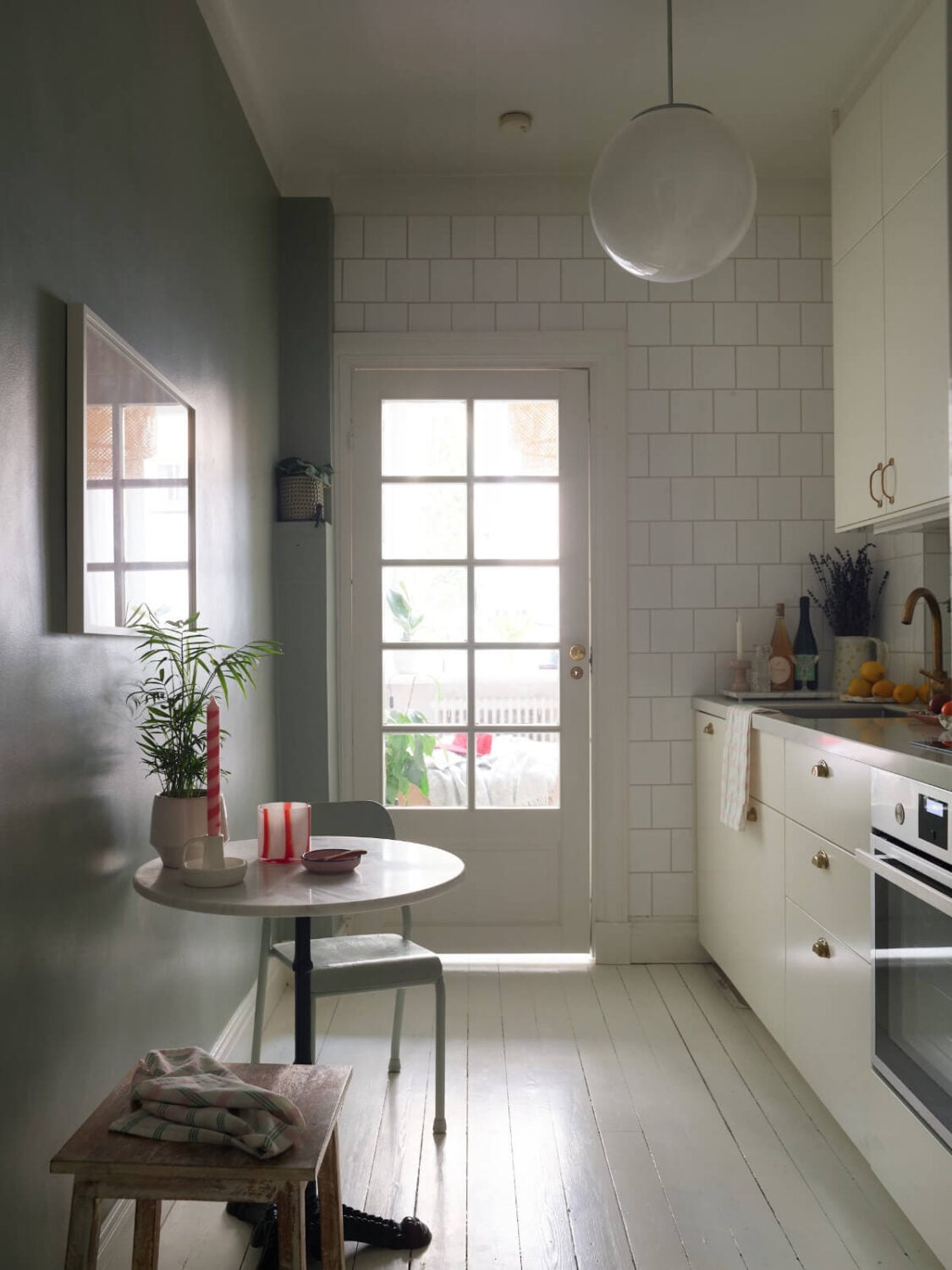 A Charming Small Apartment with a Fresh White Kitchen 10 white kitchen with small round table and glass door