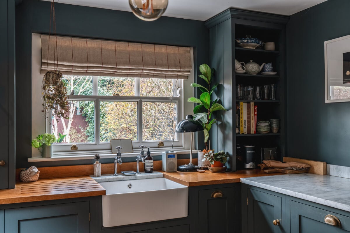 A Cozy Victorian Home Painted in Moody Blue and Gray Tones 11 dark blue kitchen butler sink under window