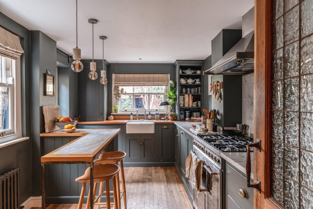 A Cozy Victorian Home Painted in Moody Blue and Gray Tones 10 dark gray kitchen with wooden floor and bar seating