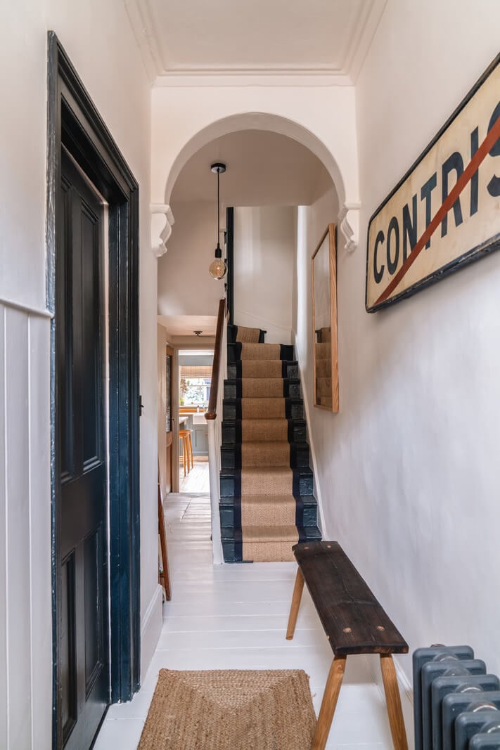 A Cozy Victorian Home Painted in Moody Blue and Gray Tones 9 hall white-painted floorboards arch
