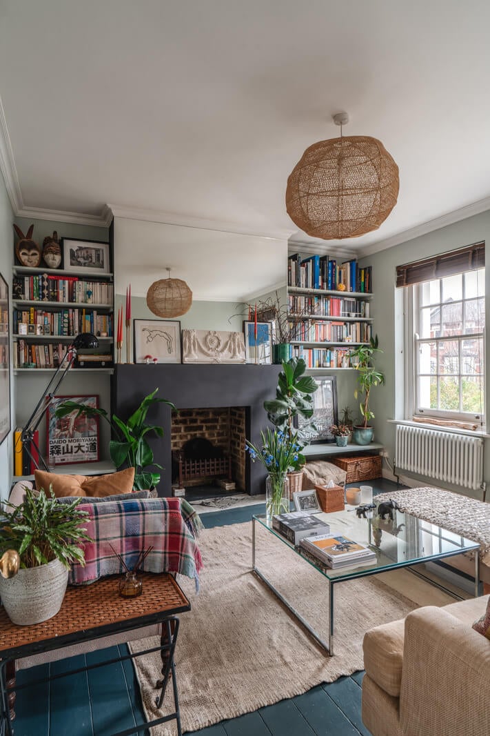 A Cozy Two-Bedroom Attic Apartment in a Victorian Townhouse 3 living room dark painted floorboards plants bookshelves fireplace