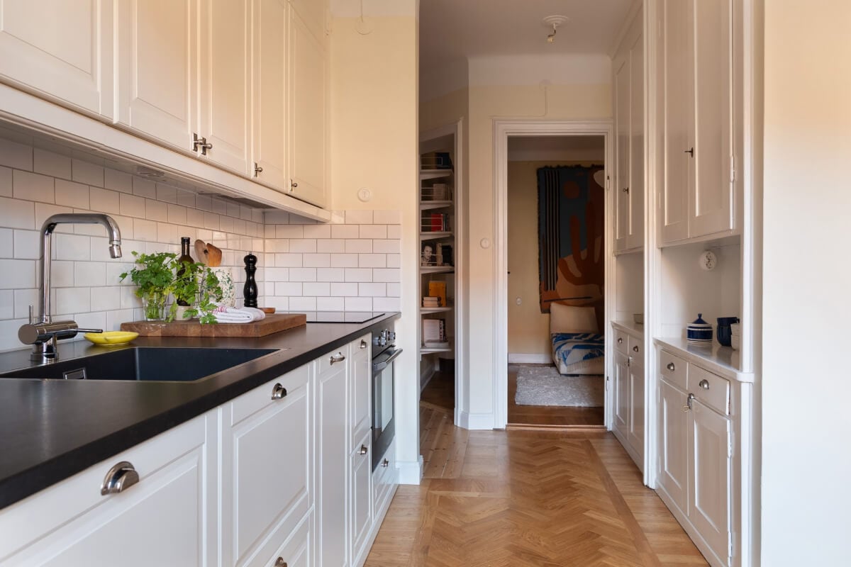 A Swedish Apartment with Period Features and Charming Color Pops 11 open kitchen classic white cabinets parquet floor