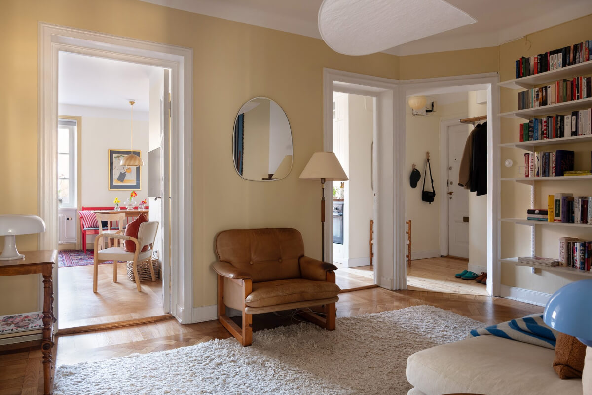 A Swedish Apartment with Period Features and Charming Color Pops 15 pale yellow inner hall with bookshelves
