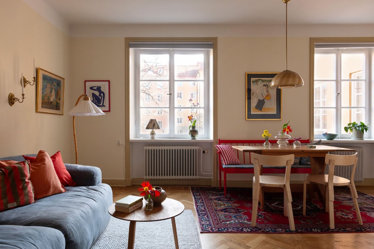 A Swedish Apartment with Period Features and Charming Color Pops 1 pale yellow living room dining table with red bench