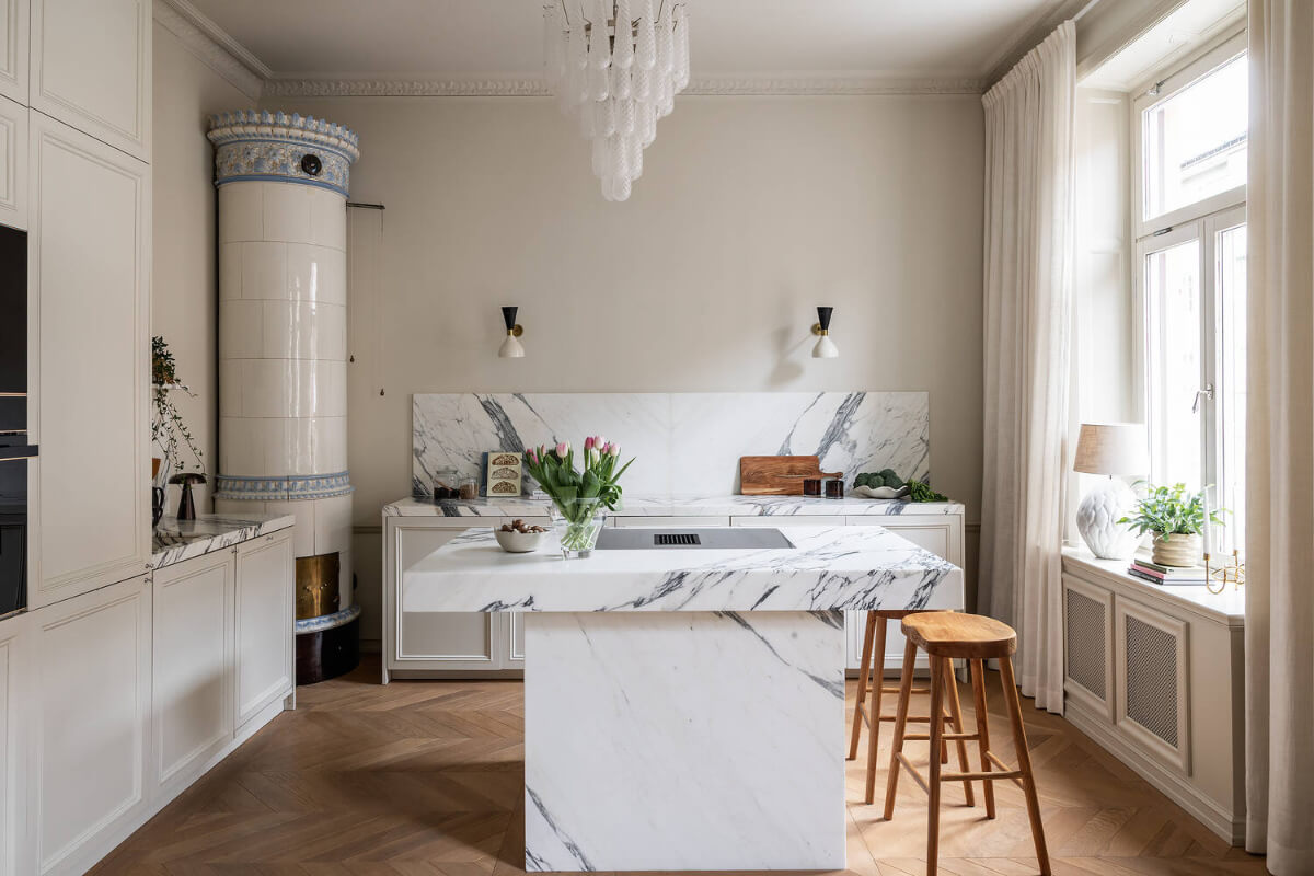 A Luxurious Stockholm Apartment with Period Features and a Blue Fireplace 9 serene-kitchen-fireplace-marble-countertop
