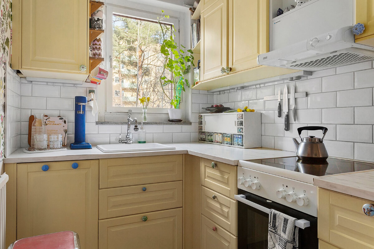 A Colorful 1940s Apartment in Stockholm 7 small yellow kitchen colorful knobs white subway tiles