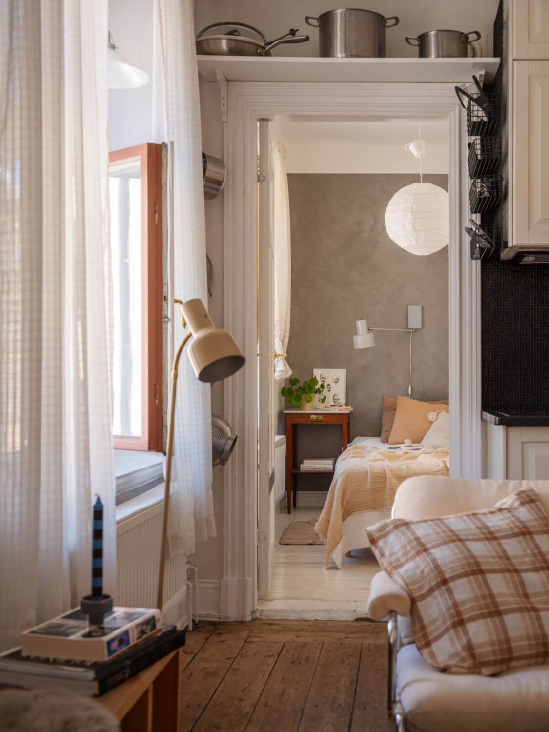 A Small Apartment with Rustic Floorboards and Beige Walls 16 view into bedroom shelf above door