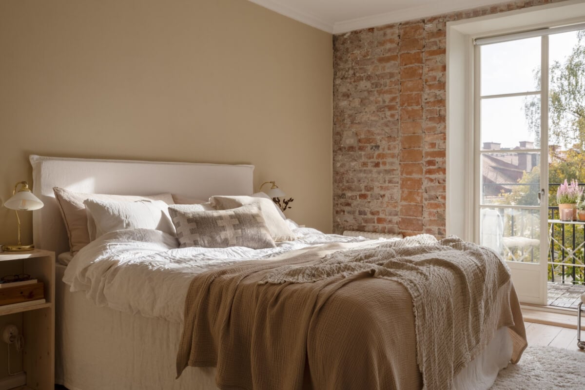A Beige Color Palette and Built-in Bookshelves in a 1920s Apartment 11 beige bedroom exposed brick wall