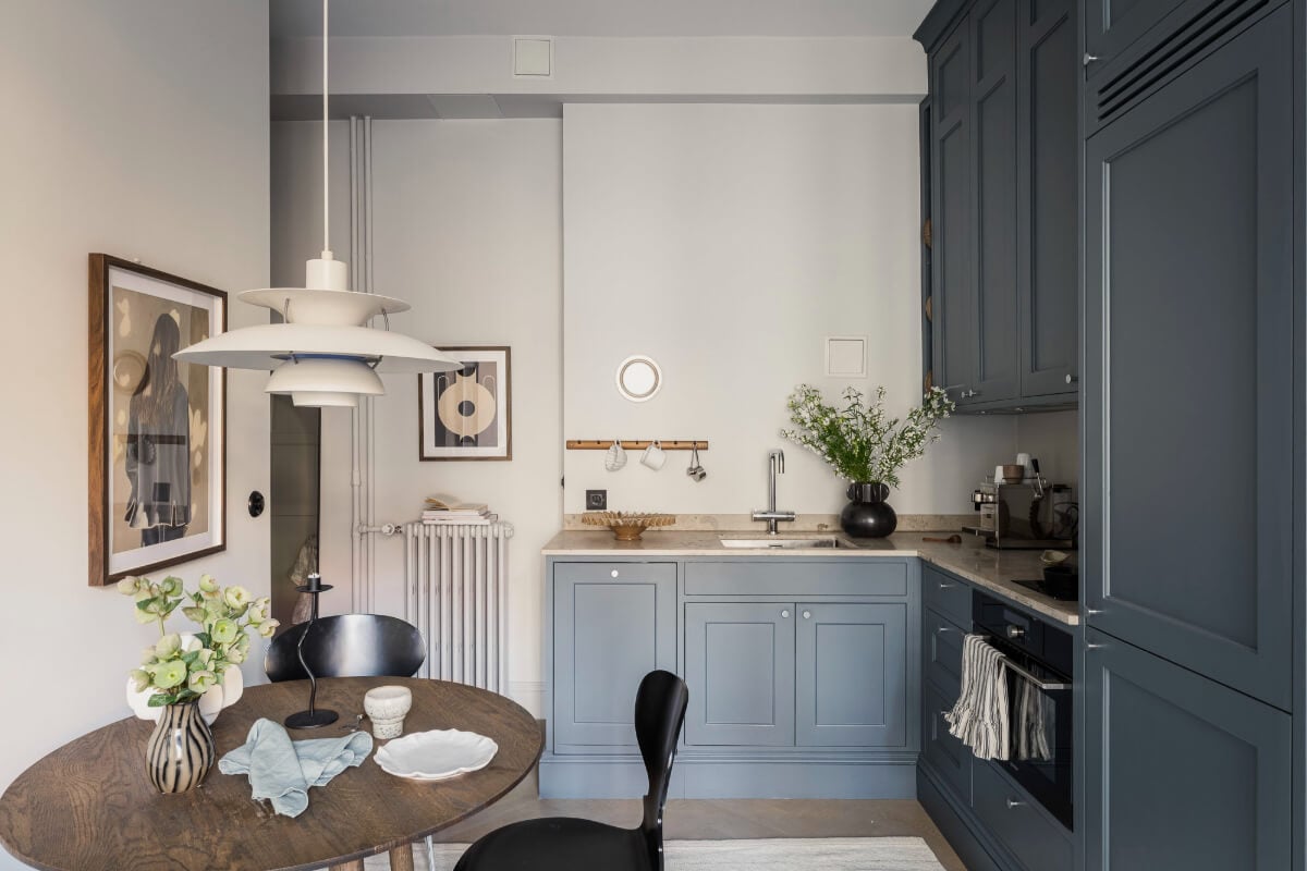 A Stylish Swedish Studio Apartment with a Blue Kitchen 2 blue kitchen with round wooden table