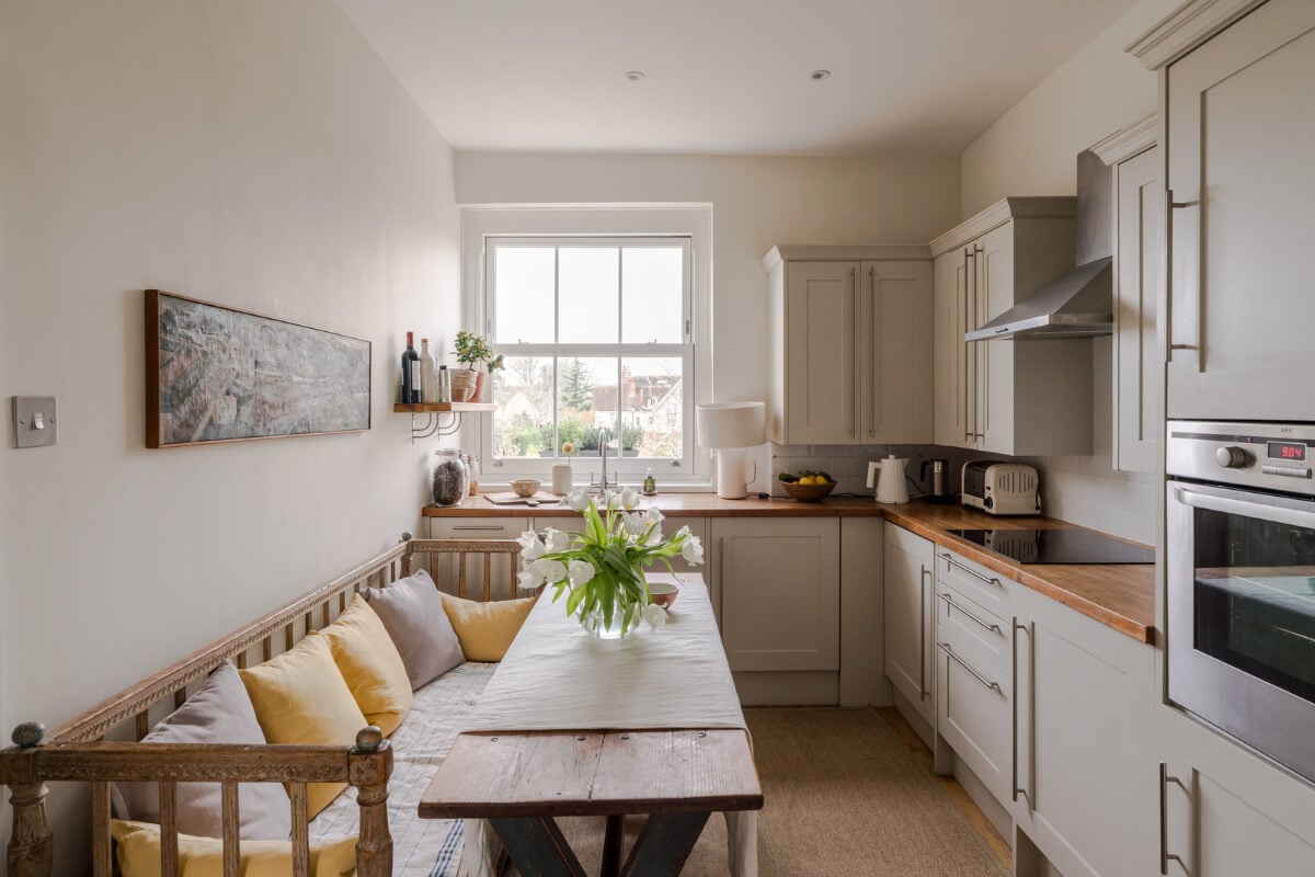 A Serene Color Palette and Arched Windows in a Small English Apartment 6 cozy light-colored kitchen rustic dining table vintage wooden bench