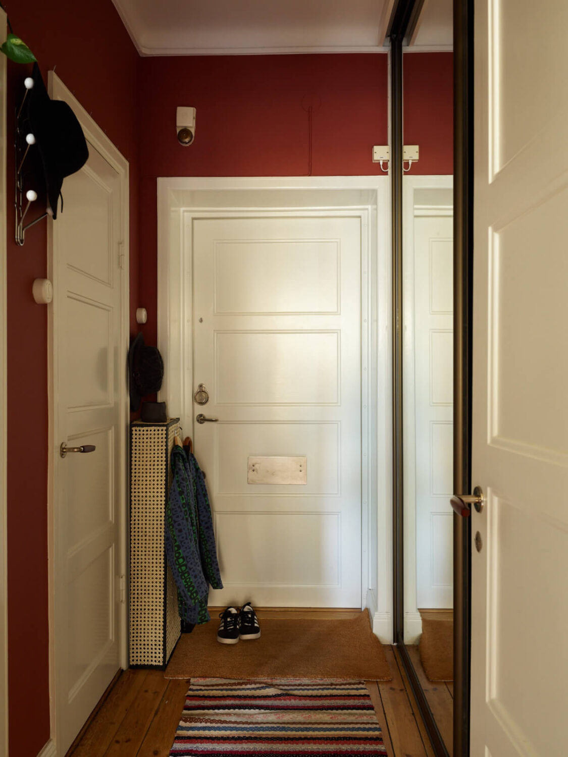 A Colorful Studio Apartment with Smart Storage and A Cozy Bed Niche 17 deep red hallway with built-in wardrobes mirror doors