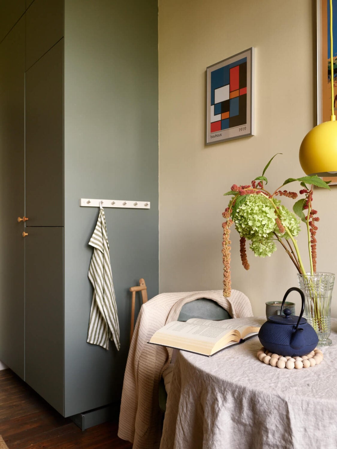 A Nature-Inspired Color Palette in a Stockholm Apartment 11 floor to ceiling kitchen cabinets small round table yellow pendant light