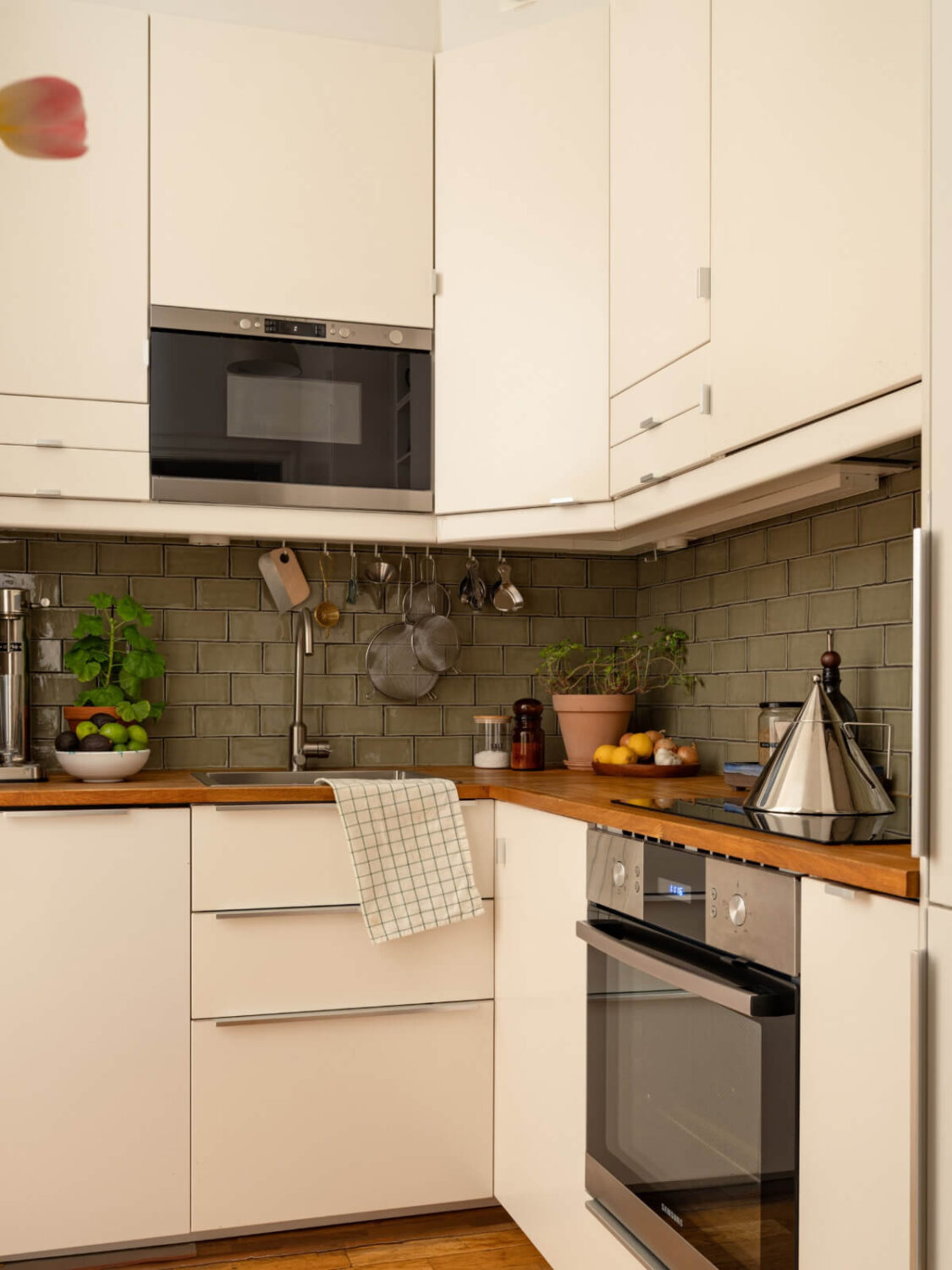 A Small, Cozy Apartment with Built-in Storage and Bookshelves 12 green backsplash tiles white kitchen cabinets