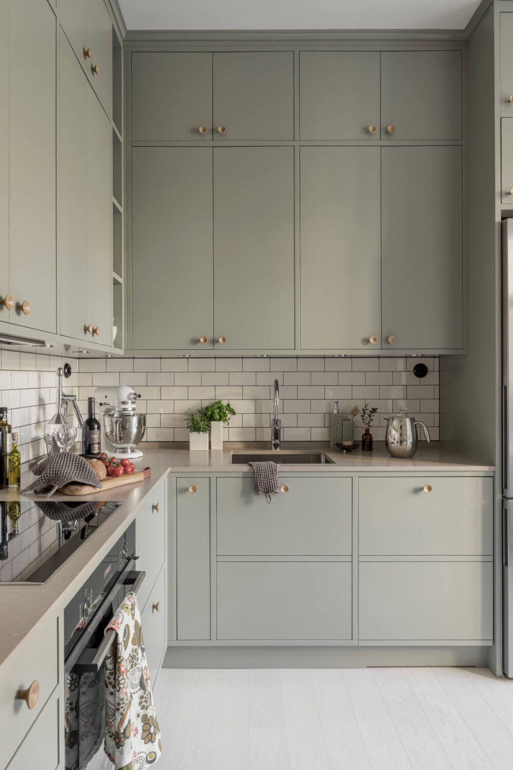 A Bright Swedish Apartment with Period Features and a Green Kitchen 2 green kitchen double upper cabinets white backsplash tiles