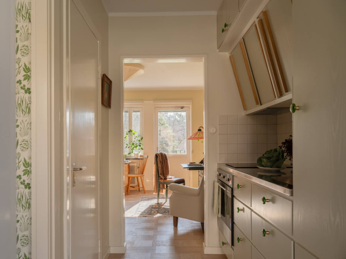 A Tiny Apartment Filled with Books and a Midcentury-Style Kitchen 16 kitchen view into living room