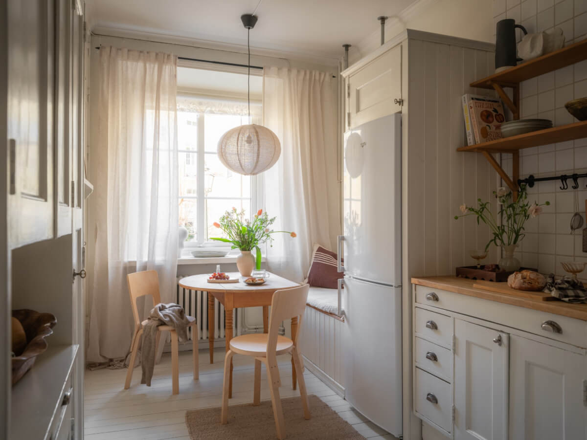 A Light-Colored Studio Apartment with a Cozy Kitchen 7 kitchen with built-in bench and dining table