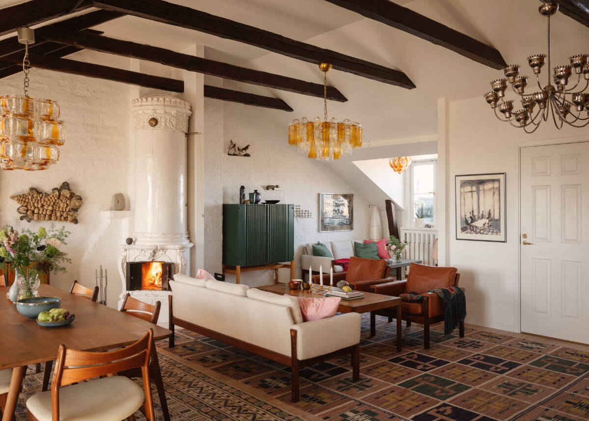 Revisiting a Spectacular Stockholm Penthouse with Exposed Beams 3 large rugs cozy seating fireplace penthouse