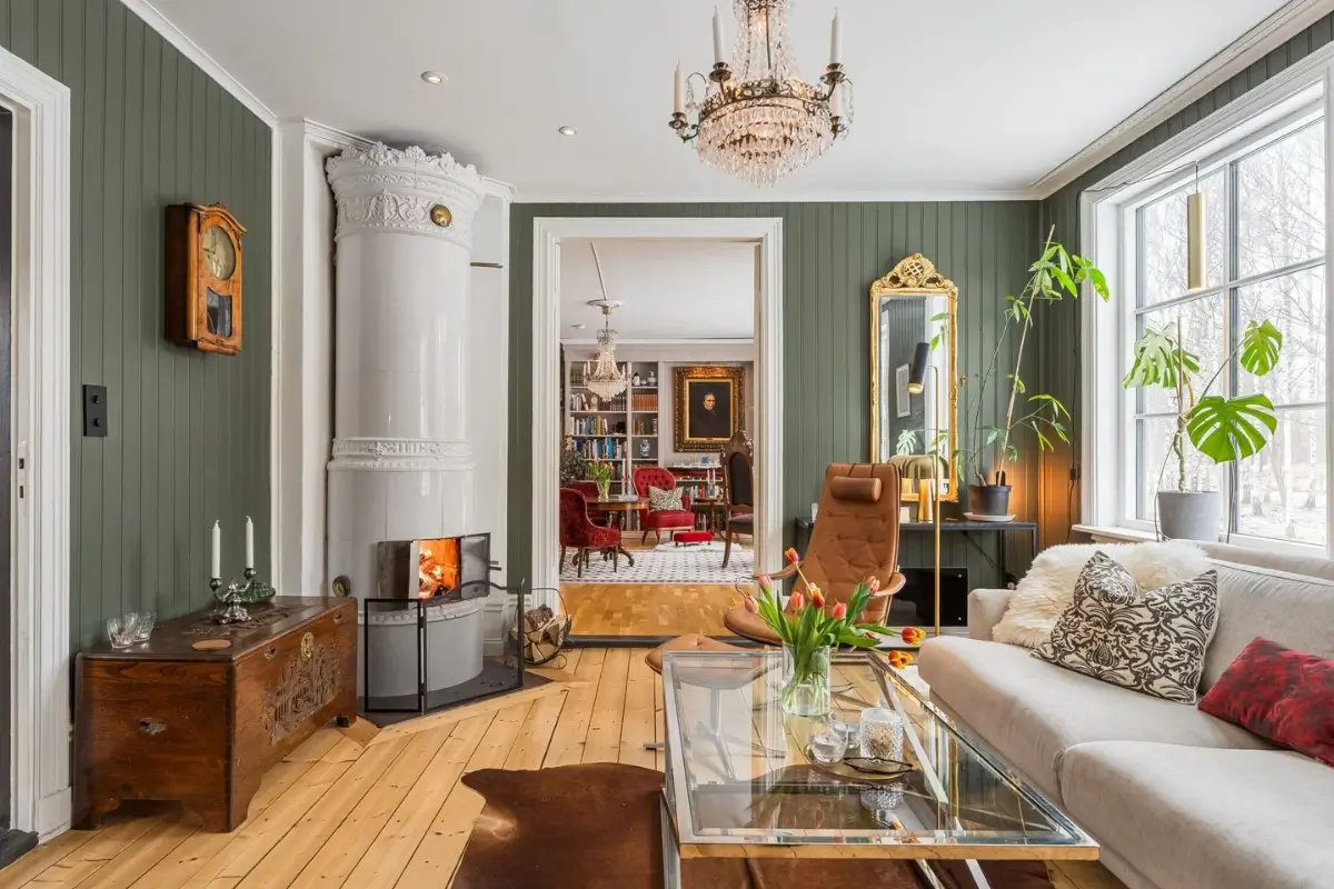 A Cozy Country House in Sweden Filled with Wallpapers 12 living room green paneling wooden floor fireplace