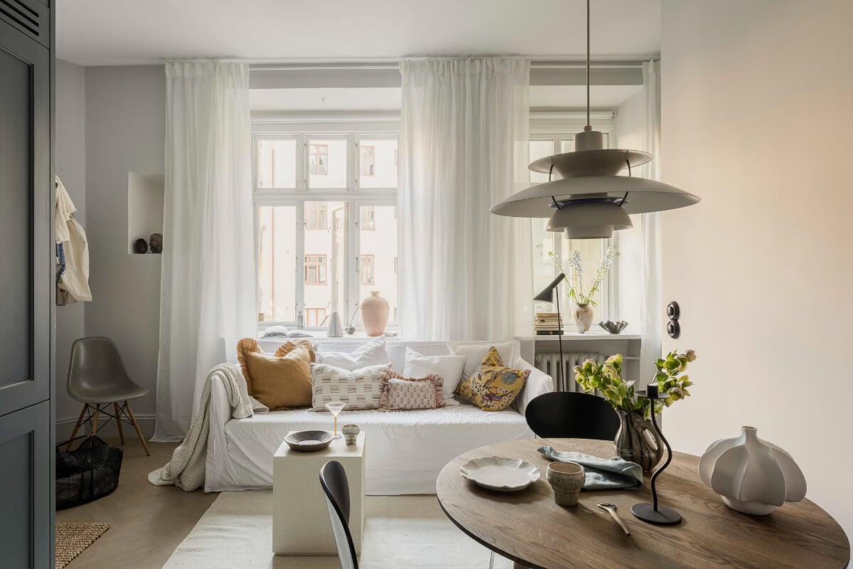 A Stylish Swedish Studio Apartment with a Blue Kitchen 6 living room large windows round dining table