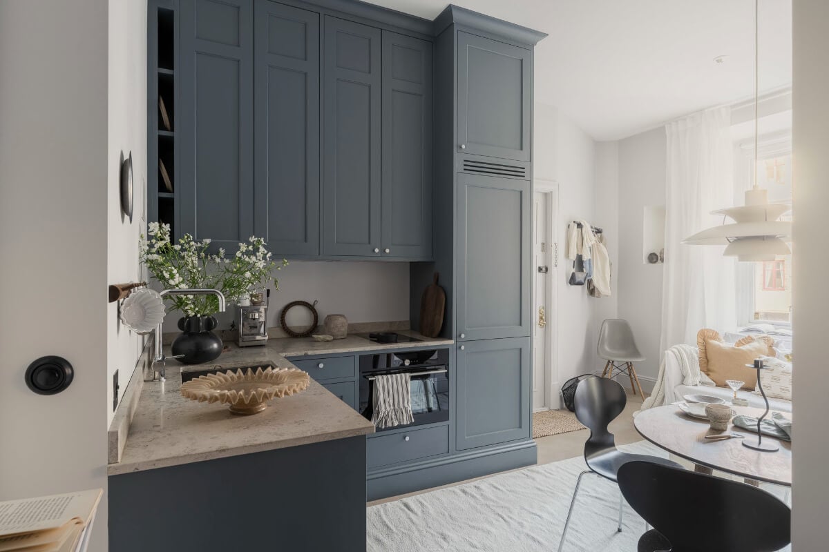 A Stylish Swedish Studio Apartment with a Blue Kitchen 1 living space with blue kitchen round table and sofa