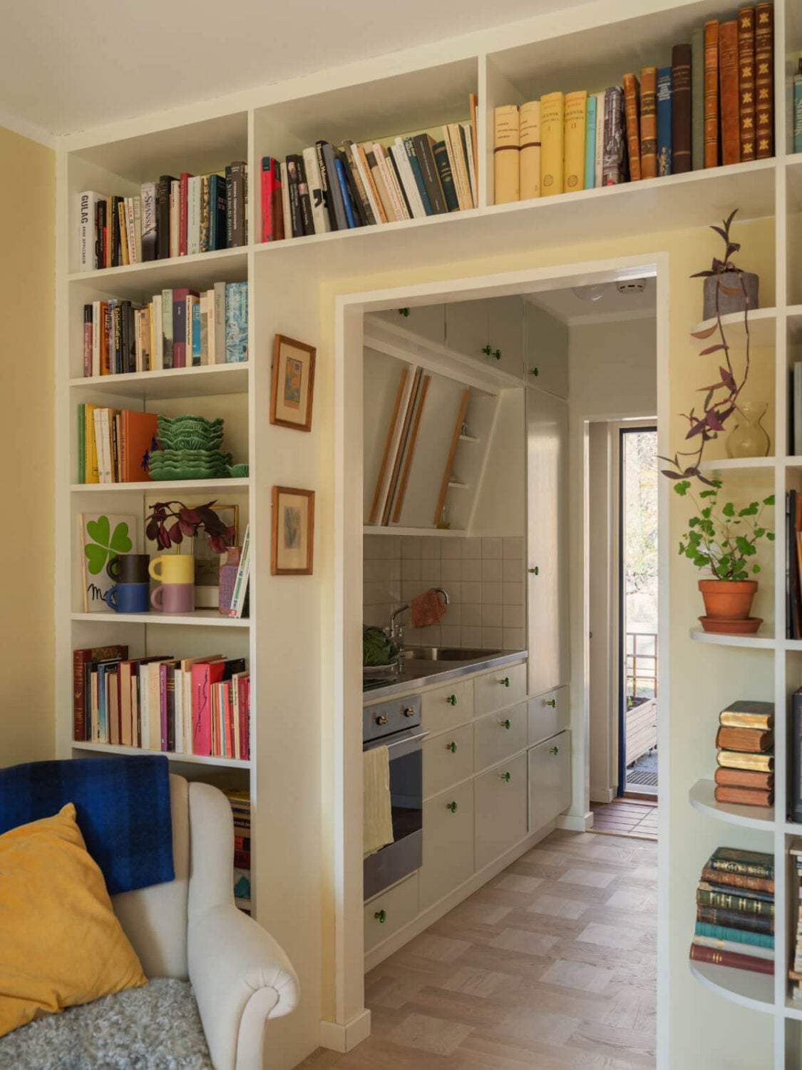 A Tiny Apartment Filled with Books and a Midcentury-Style Kitchen 15 open doorway bookshelves midcentury kitchen