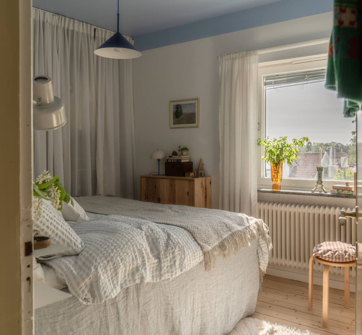 A Stylish and Joyful Color and Material Palette in a Midcentury Apartment 17 bedroom blue-painted ceiling wardrobes behind sheer curtain