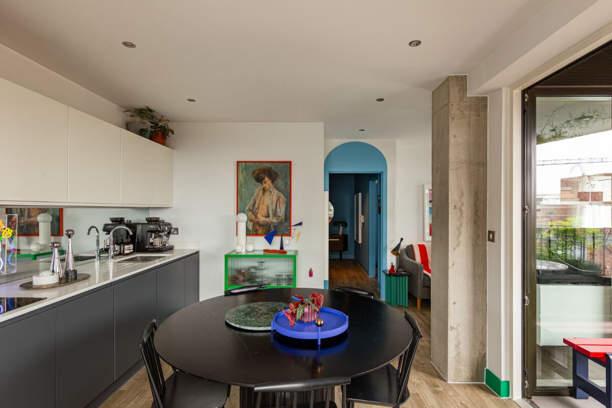 Playful Colors in a Modern One-Bedroom Apartment in London 11 blue and gray kitchen cabinets round table