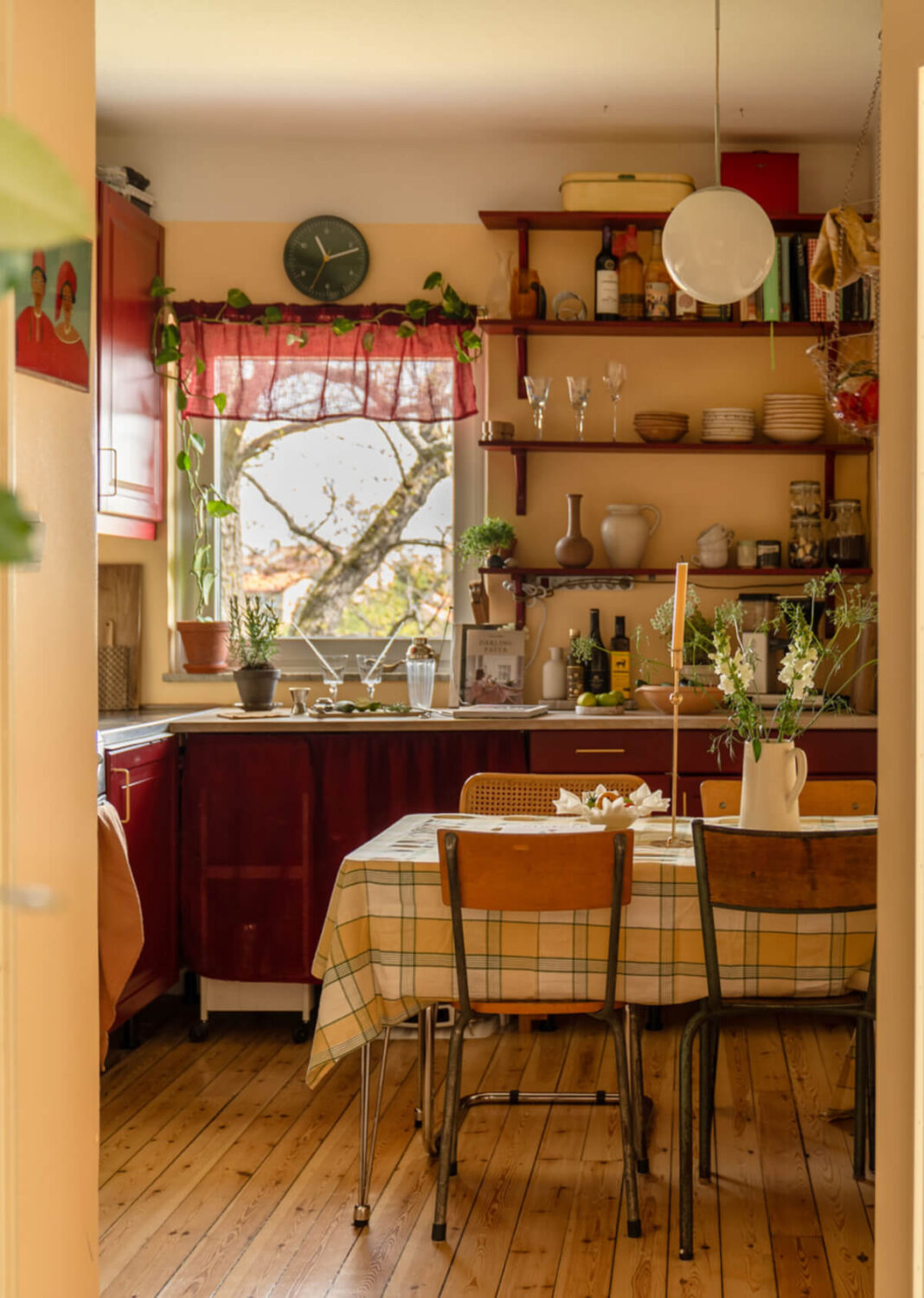 A Stylish and Joyful Color and Material Palette in a Midcentury Apartment 12 cozy kitchen wooden floor deep red cabinets yellow walls shelves nordroom
