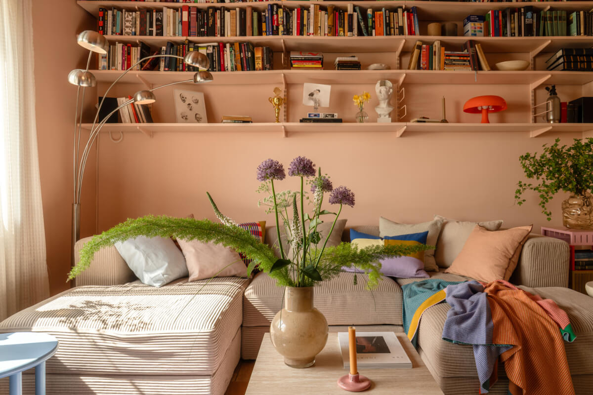 A Stylish and Joyful Color and Material Palette in a Midcentury Apartment 3 curduroy sofa pink bookshelves