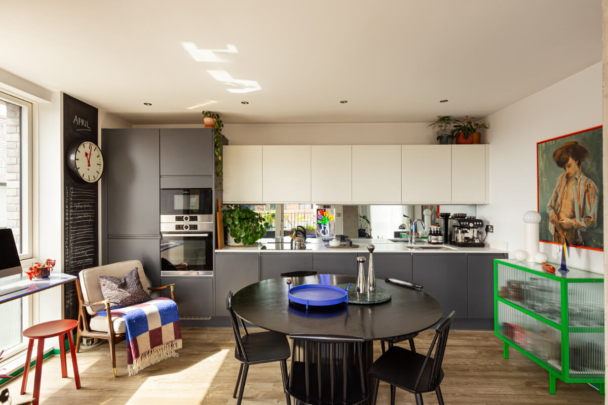 Why Everyone’s Adding Mirrors to Their Kitchens (And You Should Too) 9 gray and white kitchen mirror backsplash round dining table