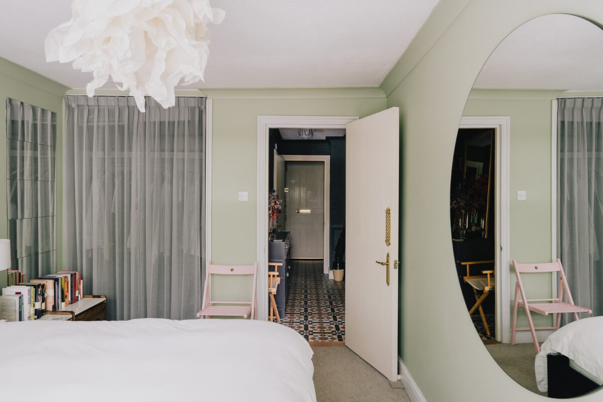 A Colorful Apartment in a Former Victorian Church in London 11 green bedroom wardrobe niche with sheer curtains