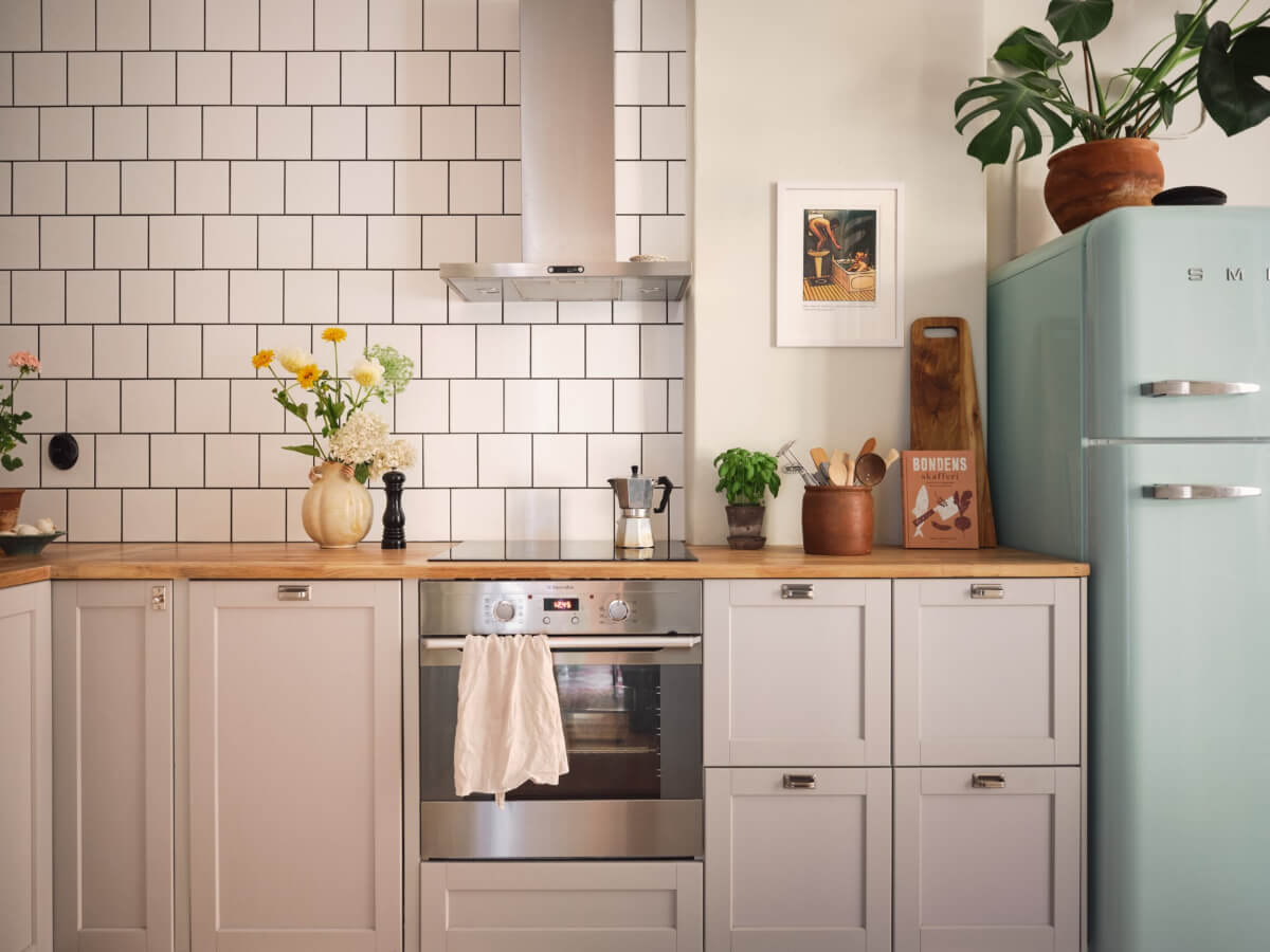 A Cozy, Tiny Apartment with a Golden Yellow Bedroom 7 kitchen light gray cabinets wooden countertop white backsplash tiles