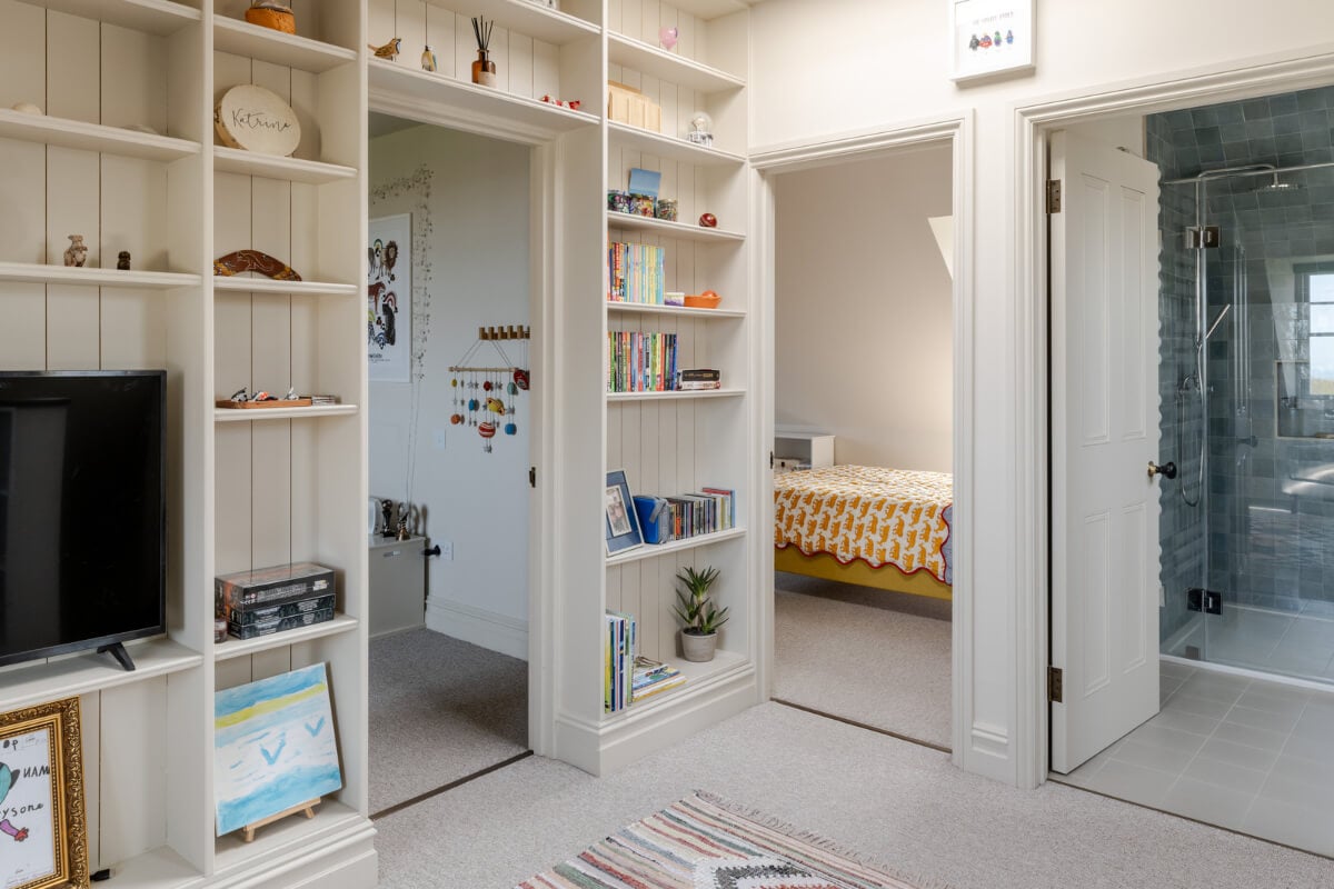 A Grand Edwardian Villa with a Yellow Kitchen and Coastal Views 26 landing with bookshelves and television