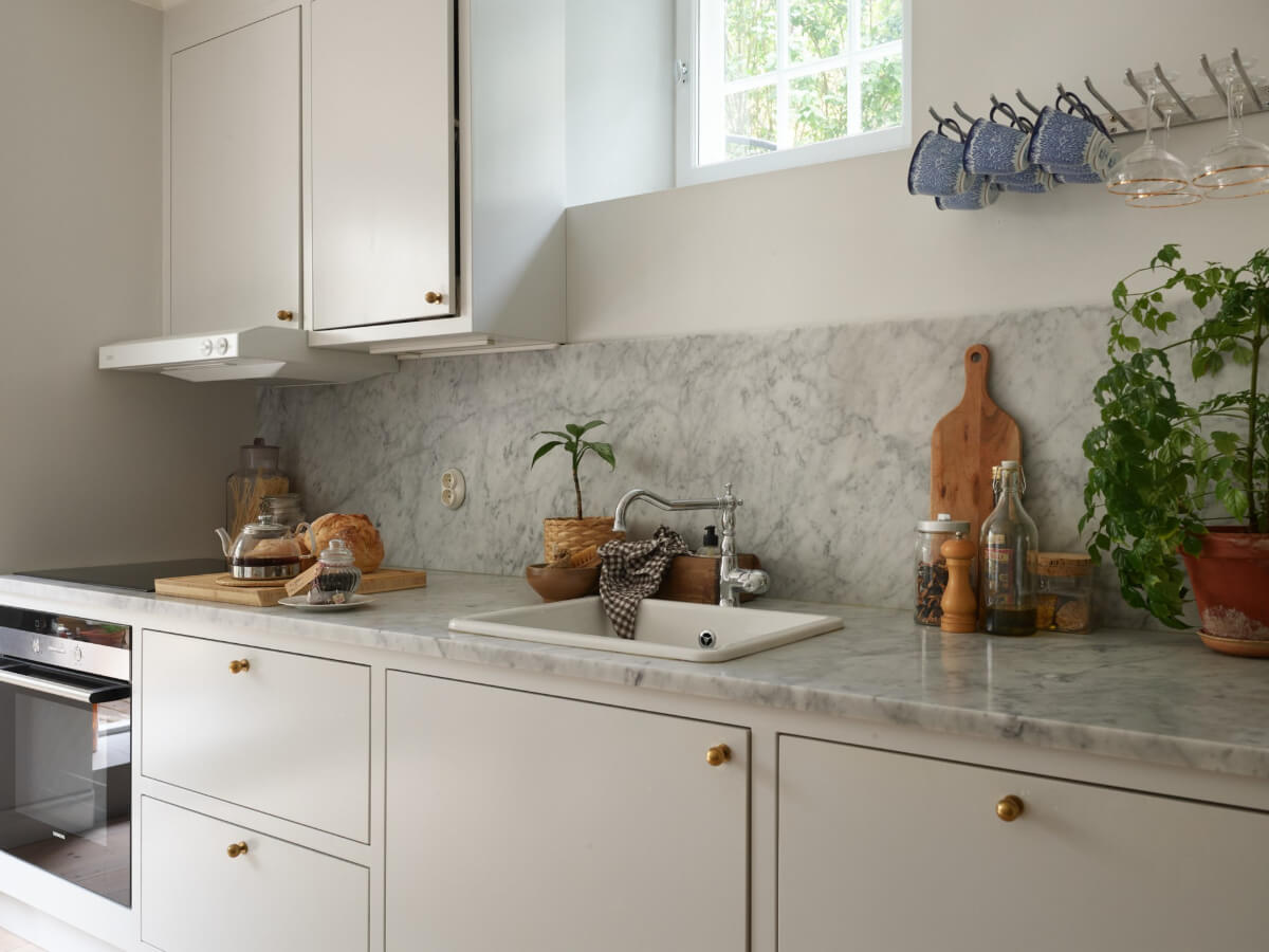 A Stylish Basement Apartment with a Private Terrace 7 light gray kitchen brass knobs marble countertop