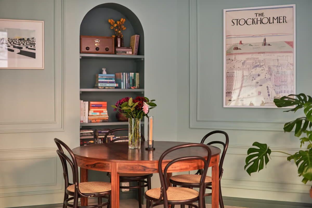 A Green Swedish Corner Apartment with an Open Floor Plan 8 round wooden dining table arched niche with bookshelves A Green Swedish Corner Apartment with an Open Floor Plan